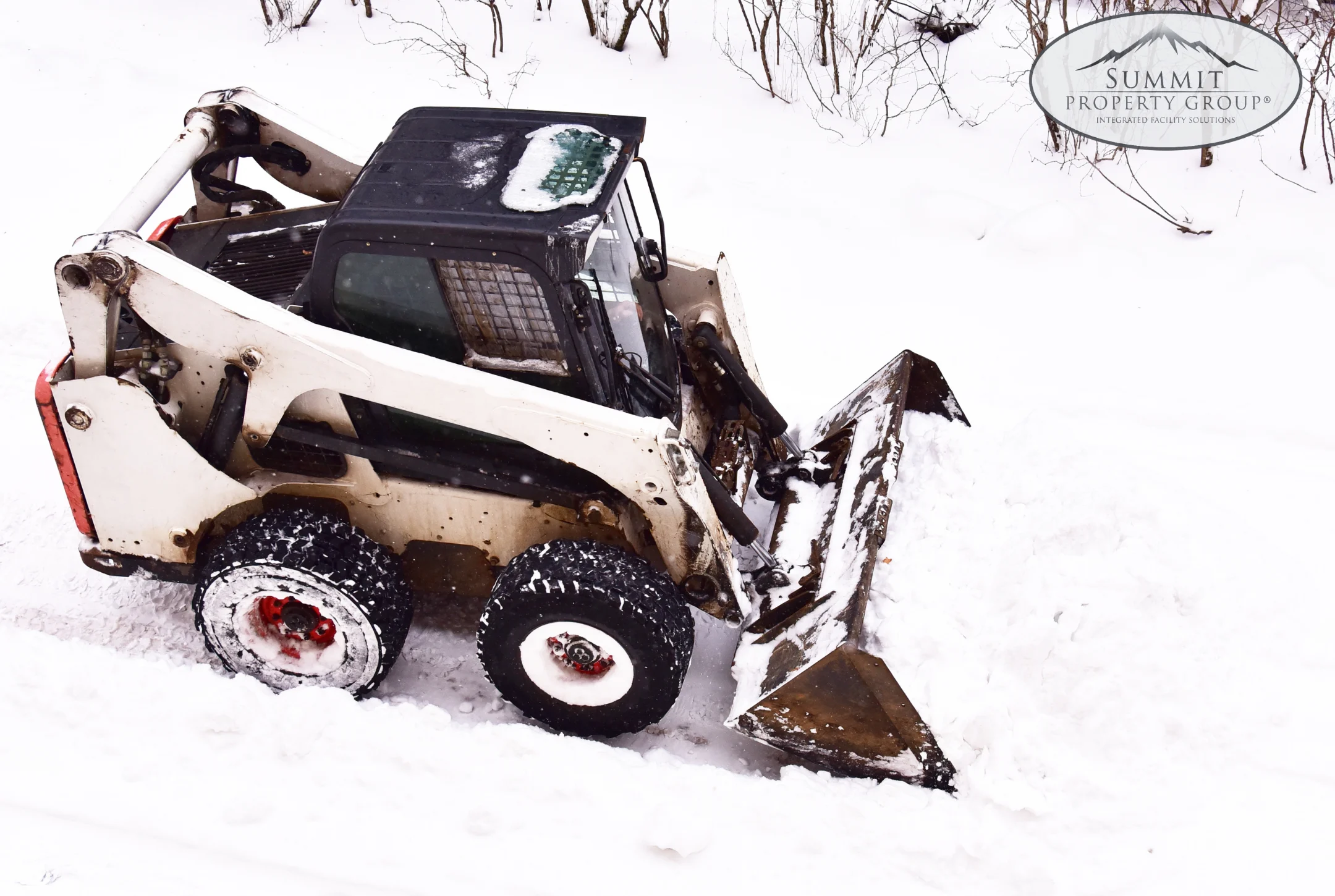 Skid steer loader clearing snow from a pathway, showcasing efficient snow removal services as part of professional winter property management in Lethbridge.