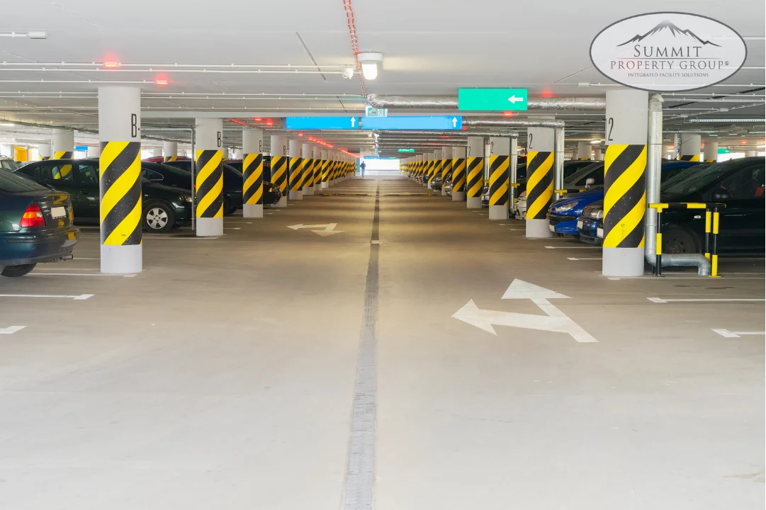 Clean and well-maintained underground parking garage with clear directional arrows and safety-striped columns, highlighting professional parking lot management and maintenance services in Lethbridge.